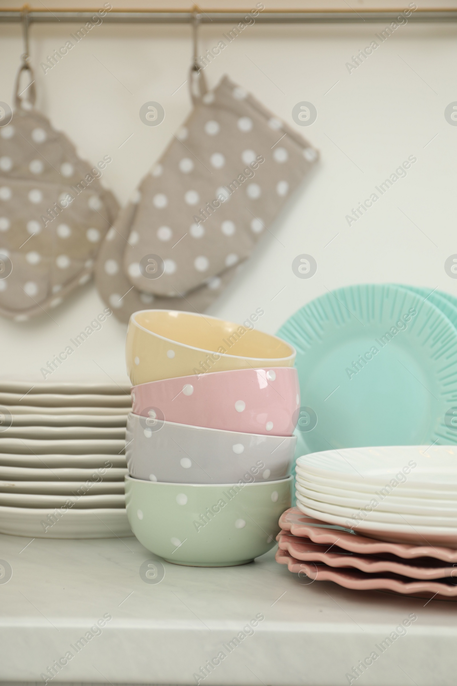 Photo of Clean plates and bowls on white marble countertop in kitchen