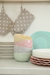 Photo of Clean plates and bowls on white marble countertop in kitchen