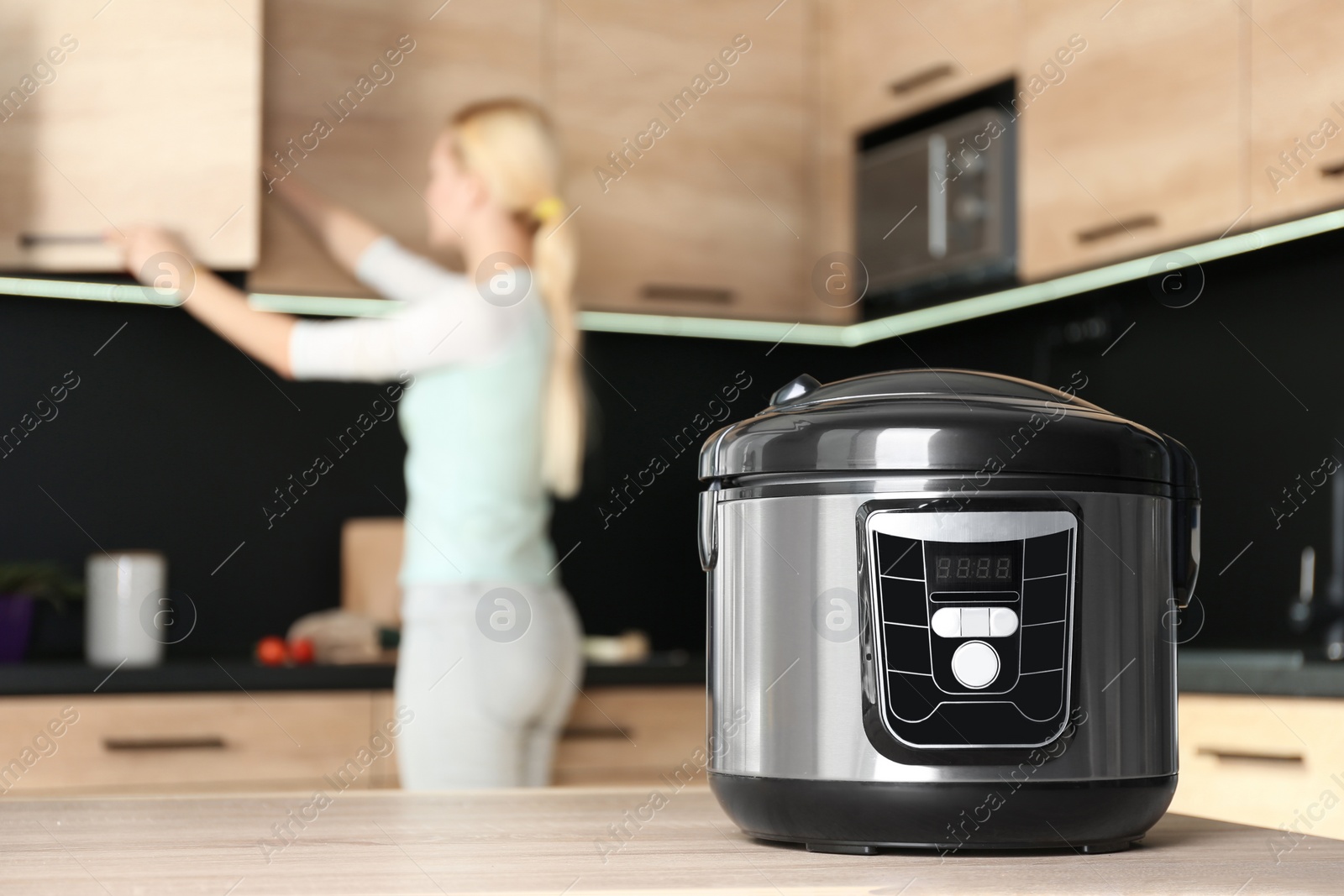 Photo of Modern multi cooker and blurred woman on background, space for text