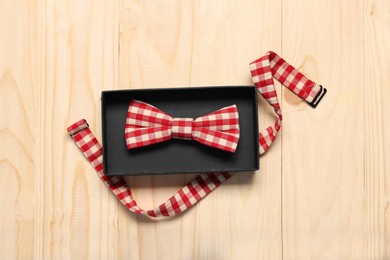 Stylish checkered bow tie on wooden table, top view