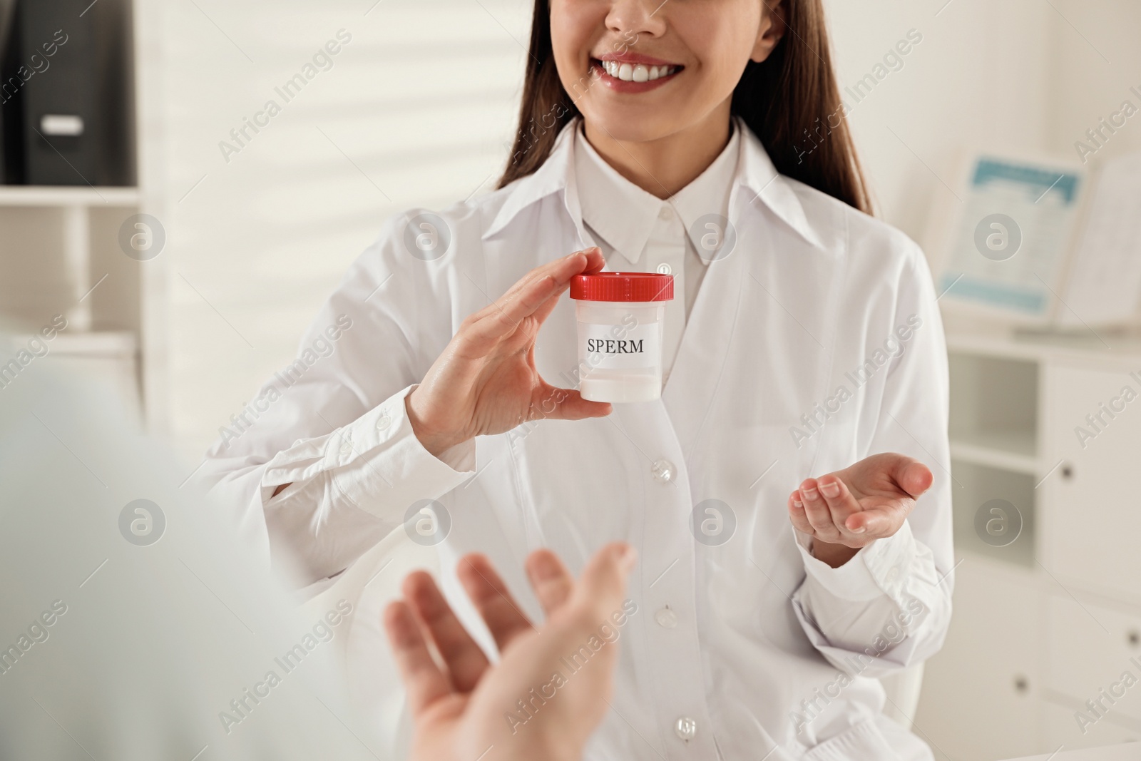 Photo of Donor giving container of sperm to doctor in hospital, closeup