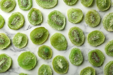 Slices of kiwi on marble background, flat lay. Dried fruit as healthy food