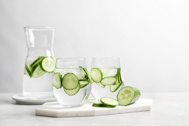 Photo of Fresh cucumber water in glassware on table against light background. Space for text