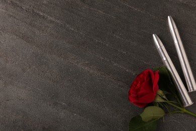 Photo of Bullets and beautiful rose on dark grey table, flat lay. Space for text