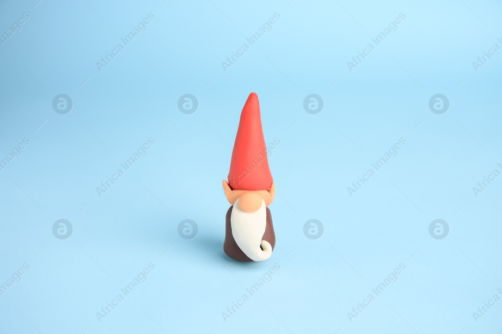 Photo of Dwarf made from plasticine on light blue background. Children's handmade ideas