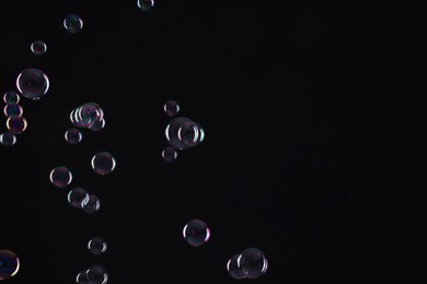 Many beautiful soap bubbles on black background. Space for text