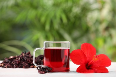 Delicious hibiscus tea and flowers on white wooden table outdoors, space for text