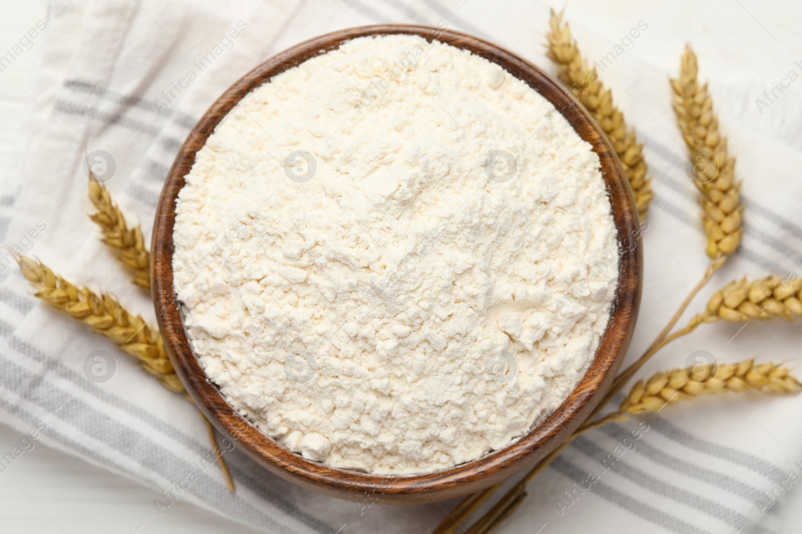 Photo of Bowl of organic wheat flour on white wooden table, top view