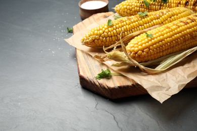 Composition with tasty grilled corn on black table