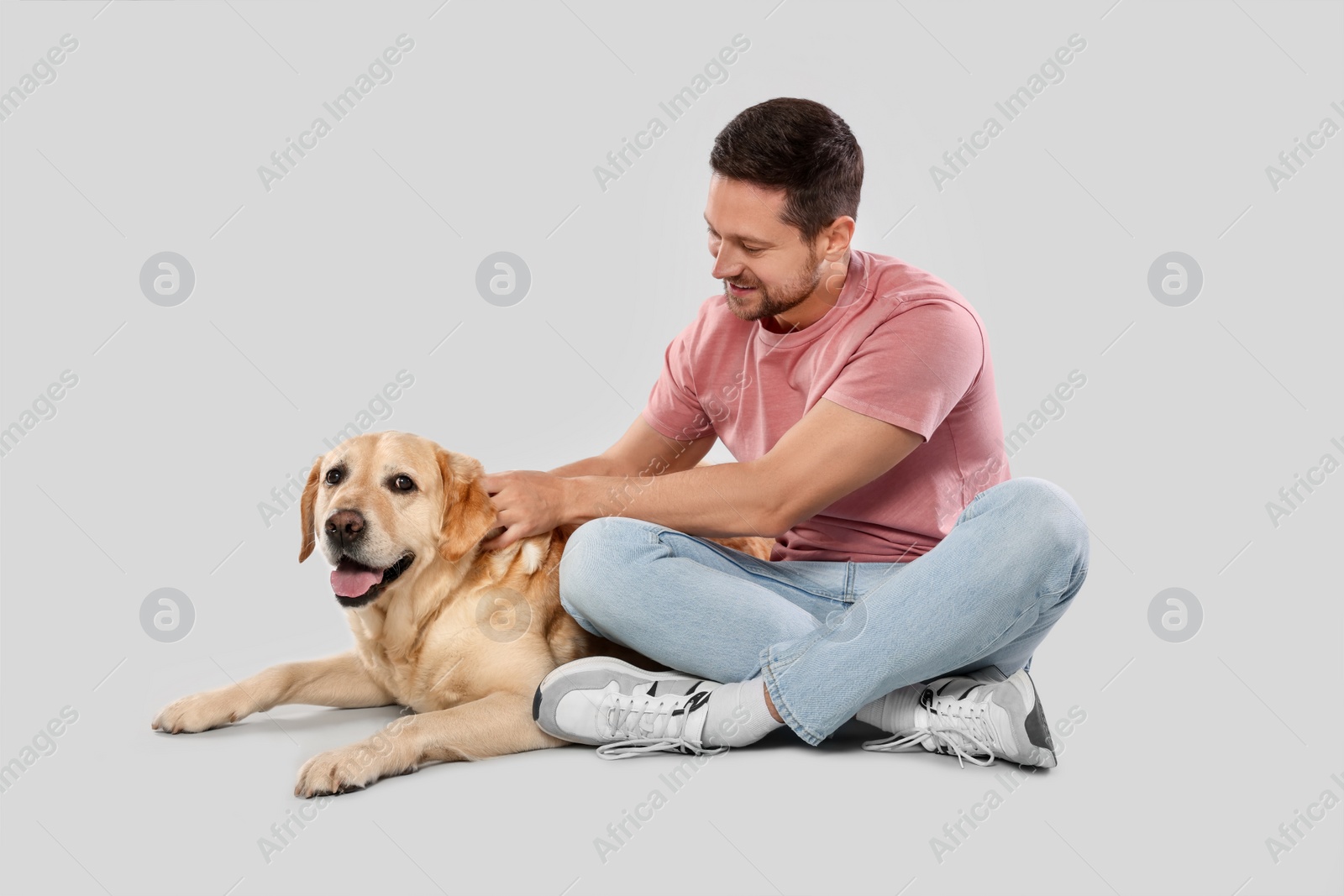 Photo of Man with adorable Labrador Retriever dog on light gray background. Lovely pet