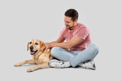 Photo of Man with adorable Labrador Retriever dog on light gray background. Lovely pet