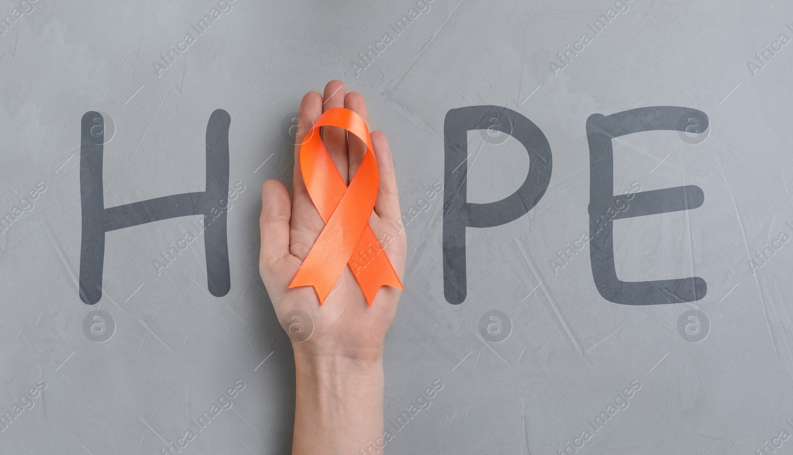 Image of Word HOPE and woman with orange awareness ribbon on light grey background, top view  