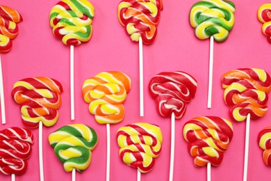 Photo of Sweet lollipops on pink background, flat lay