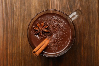 Photo of Cup of delicious hot chocolate with cinnamon stick and anise on wooden table, top view