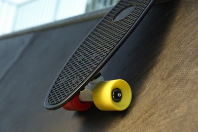 Modern black skateboard on ramp outdoors, closeup