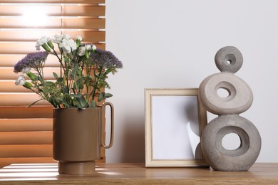 Photo of Stylish ceramic vase with beautiful flowers and decor on wooden table near window