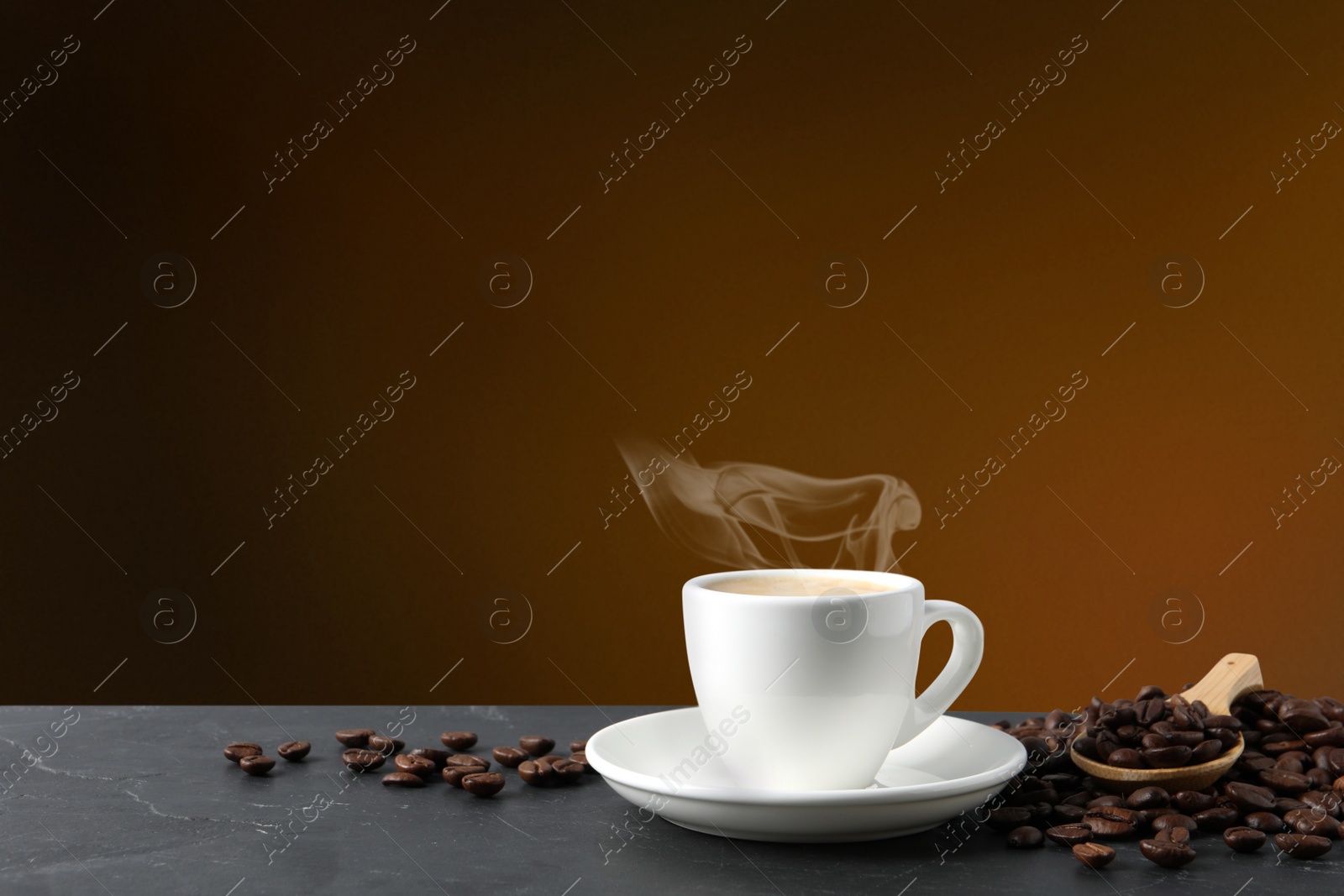 Image of Cup of hot aromatic coffee and roasted beans on black table against brown background. Space for text