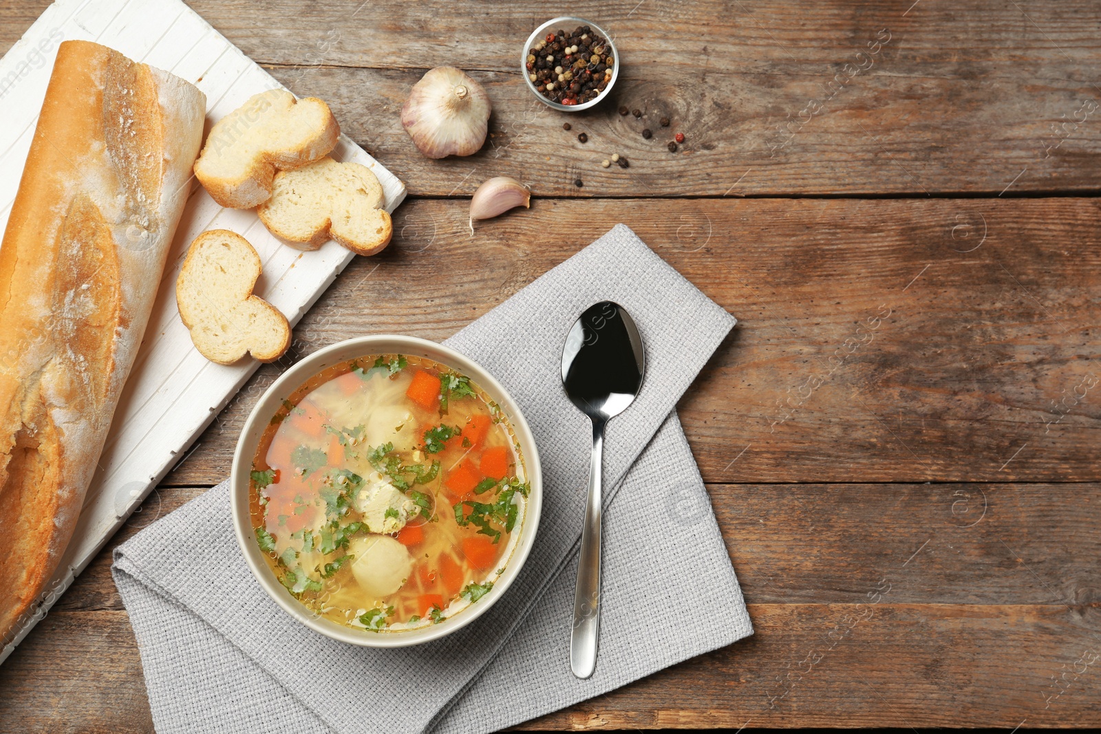 Photo of Homemade chicken soup served on wooden table, top view with space for text