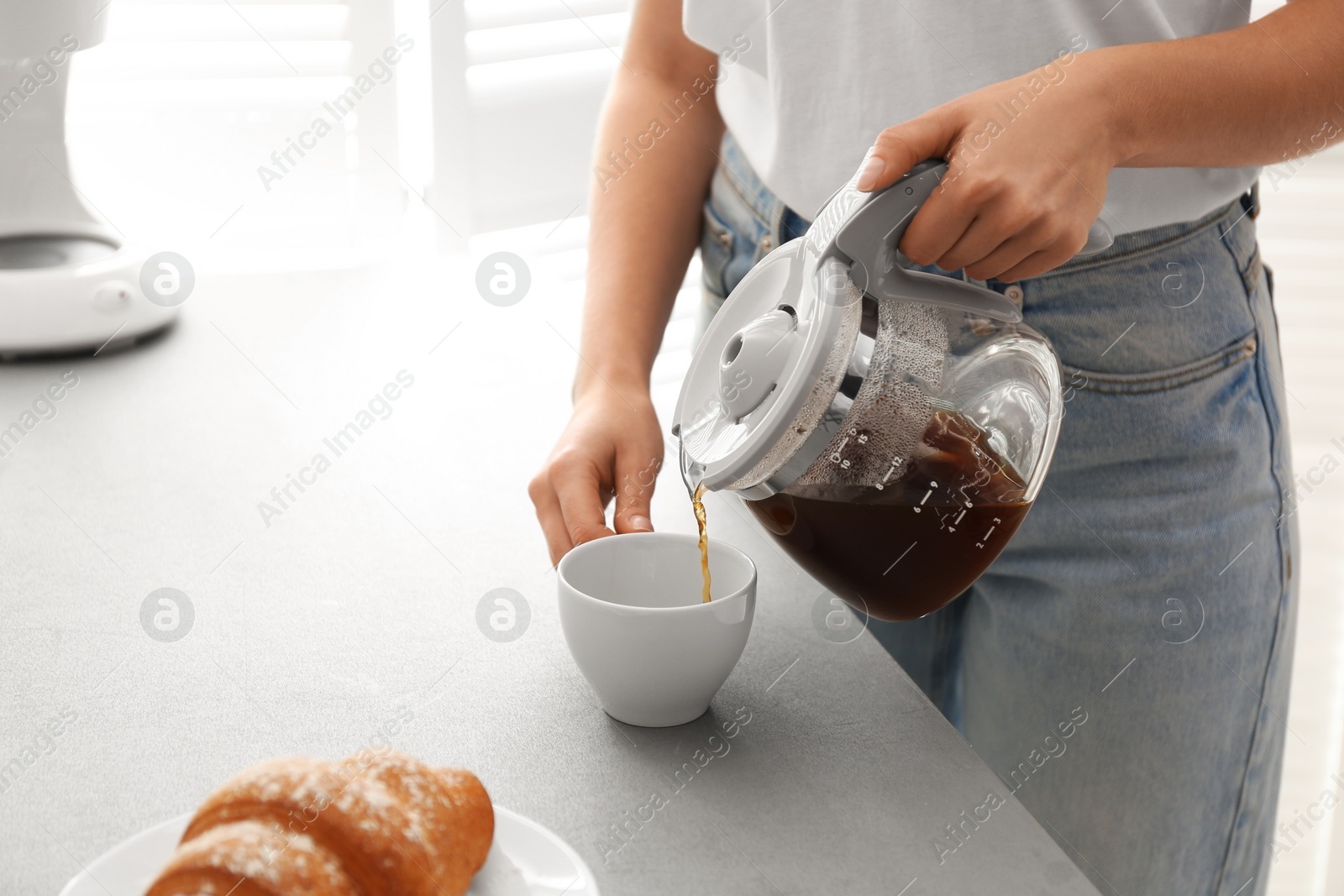 Photo of Woman pouring coffee into cup at home, closeup. Morning routine