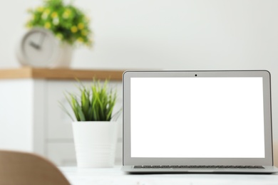 Photo of Laptop with blank screen on table indoors. Space for text