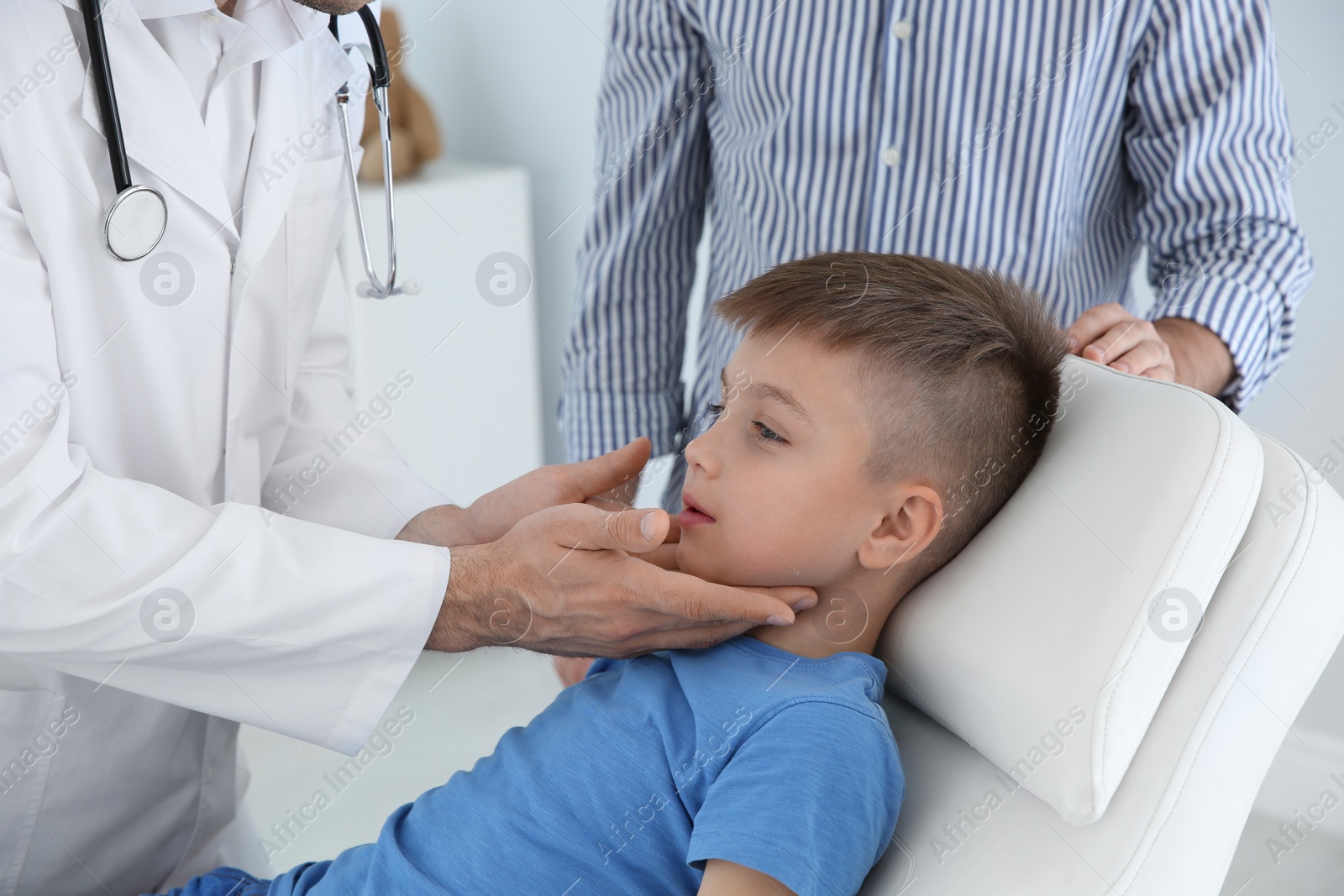 Photo of Father and son visiting pediatrician. Doctor working with patient in hospital