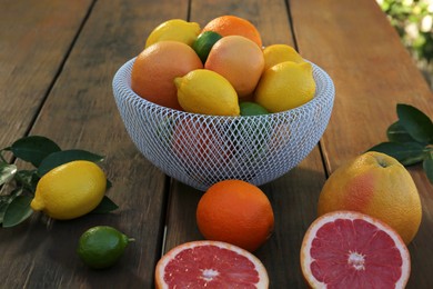 Different citrus fruits and leaves on wooden table