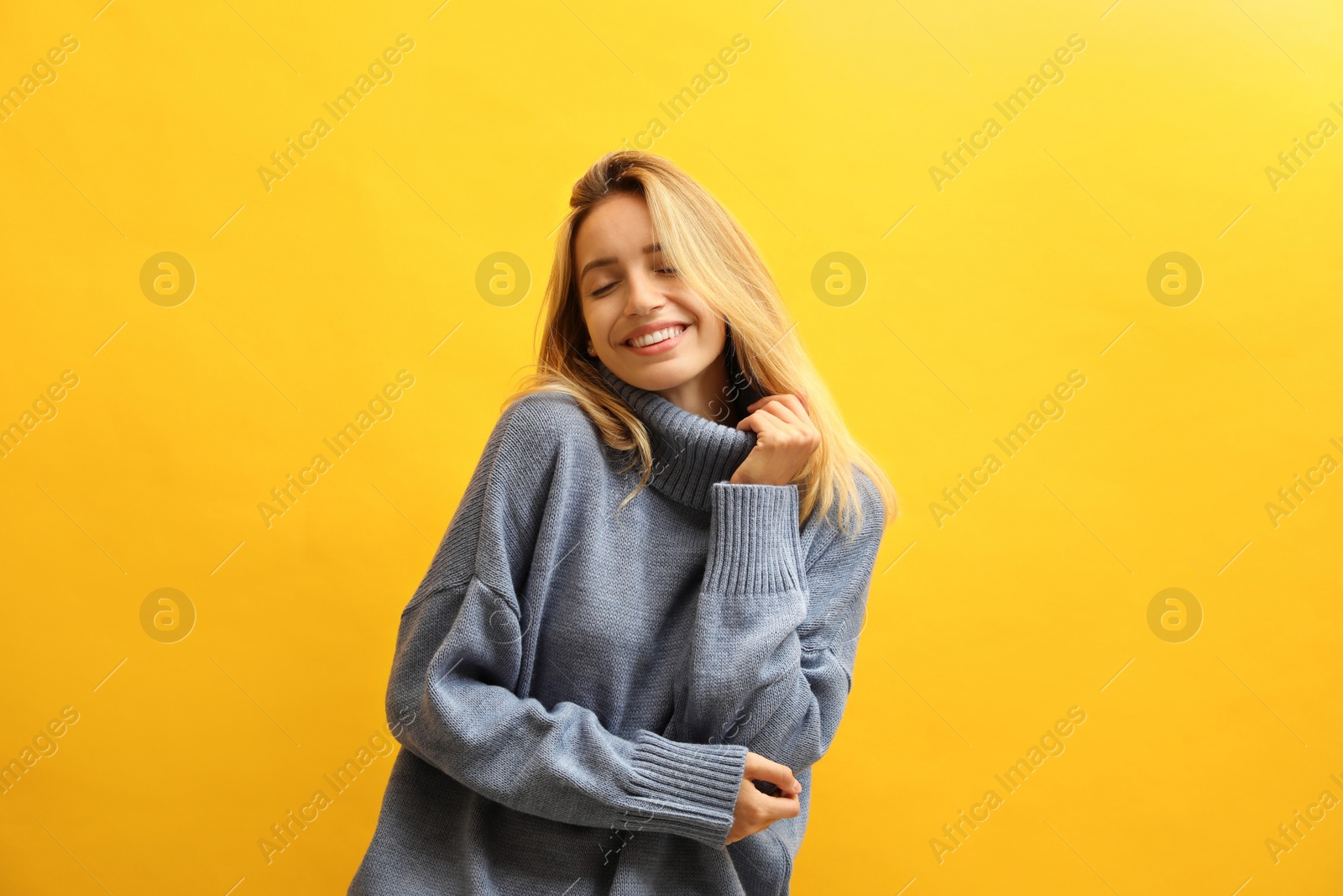 Photo of Beautiful young woman wearing knitted sweater on yellow background