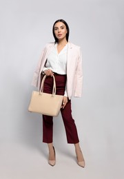 Young woman with stylish bag on white background