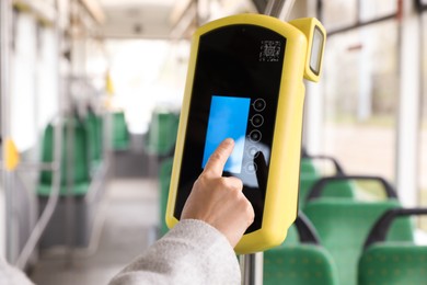 Photo of Woman using contactless fare payment device in public transport, closeup