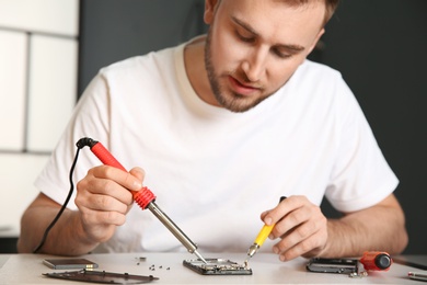 Photo of Technician repairing mobile phone at table in workshop