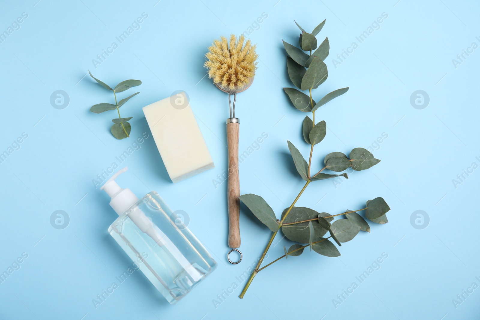 Photo of Cleaning supplies for dish washing and eucalyptus branches on light blue background, flat lay