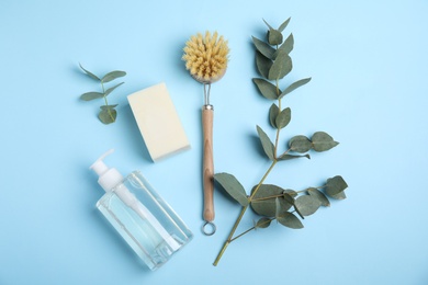 Photo of Cleaning supplies for dish washing and eucalyptus branches on light blue background, flat lay