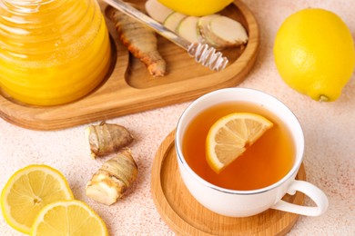 Tea, honey, lemon and ginger on beige textured table, above view