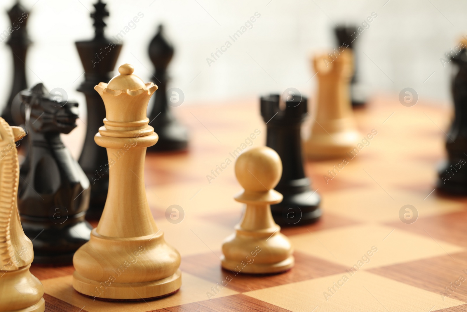 Photo of Chessboard with game pieces on light background, closeup