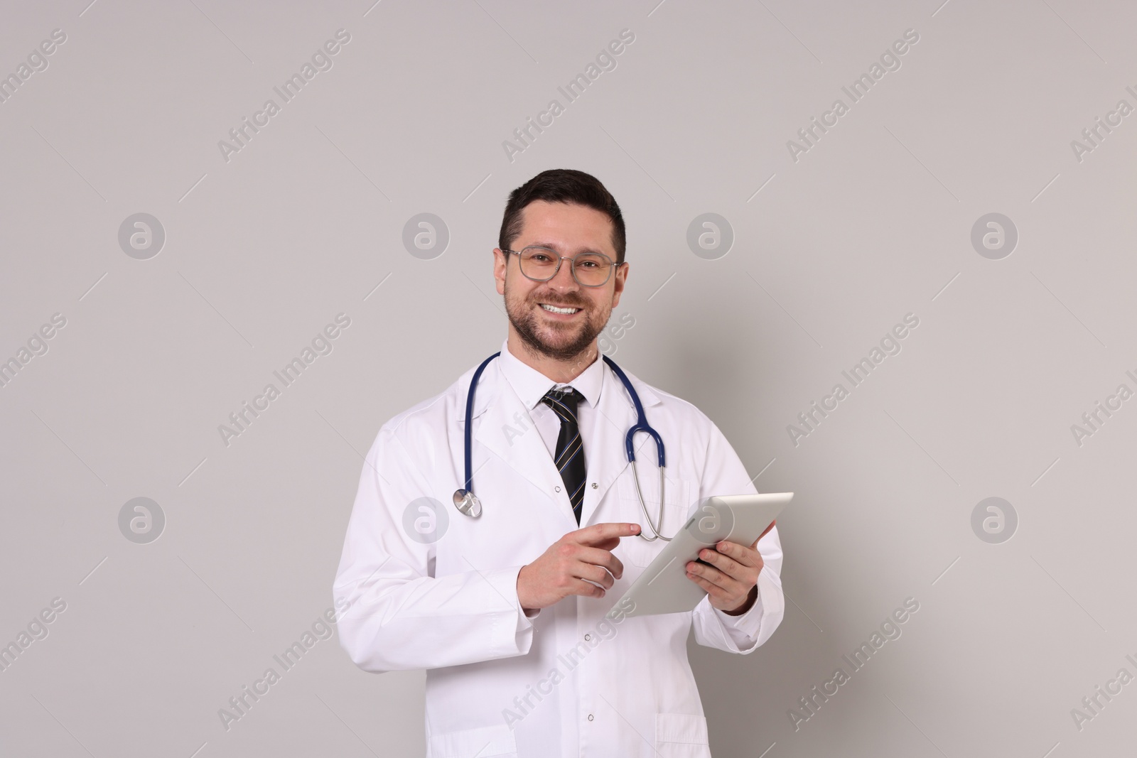 Photo of Portrait of smiling doctor with tablet on light grey background