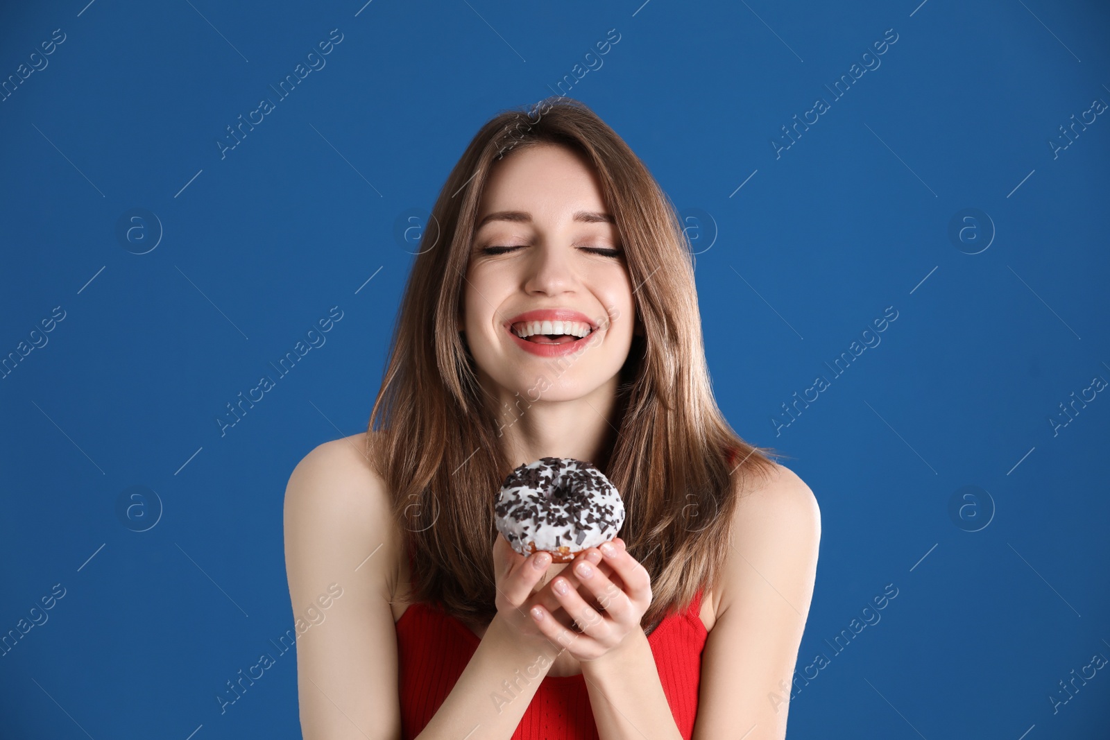 Photo of Beautiful young woman with donut on blue background