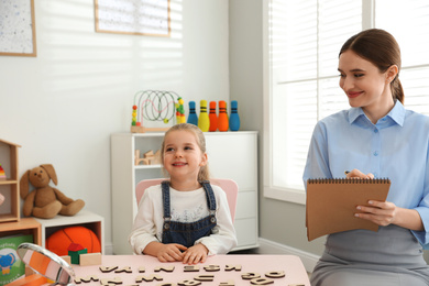 Photo of Speech therapist working with little girl in office