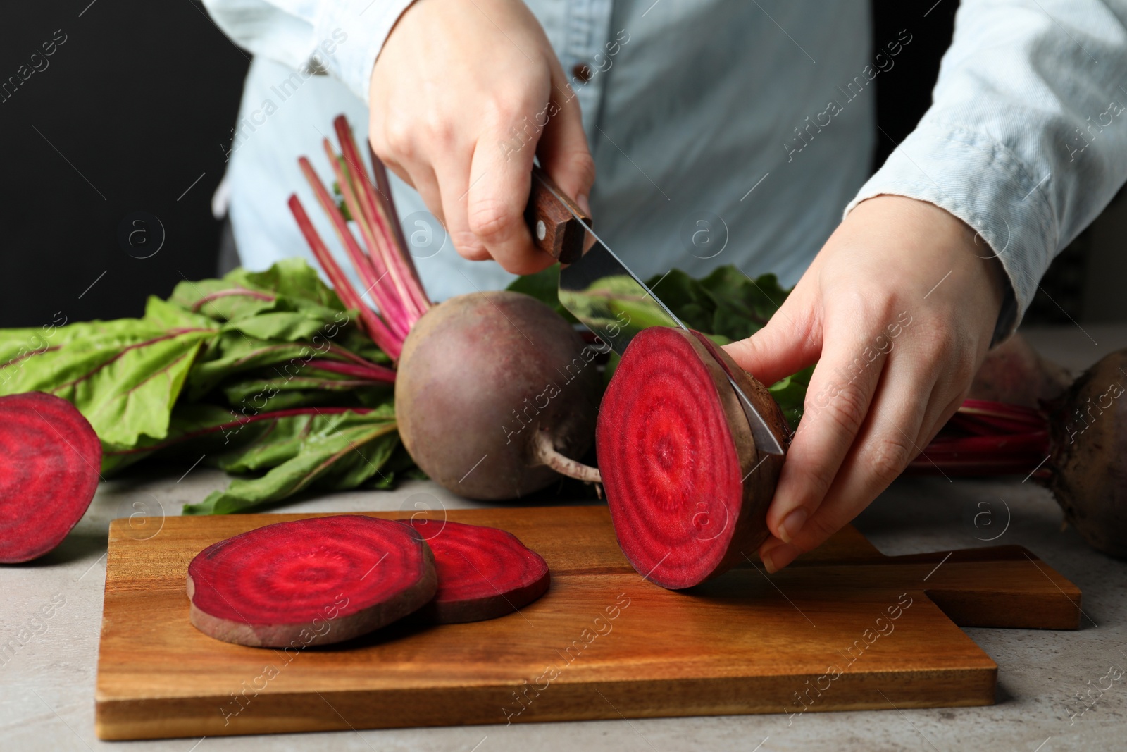 Photo of Woman cutting fresh red beet at table, closeup