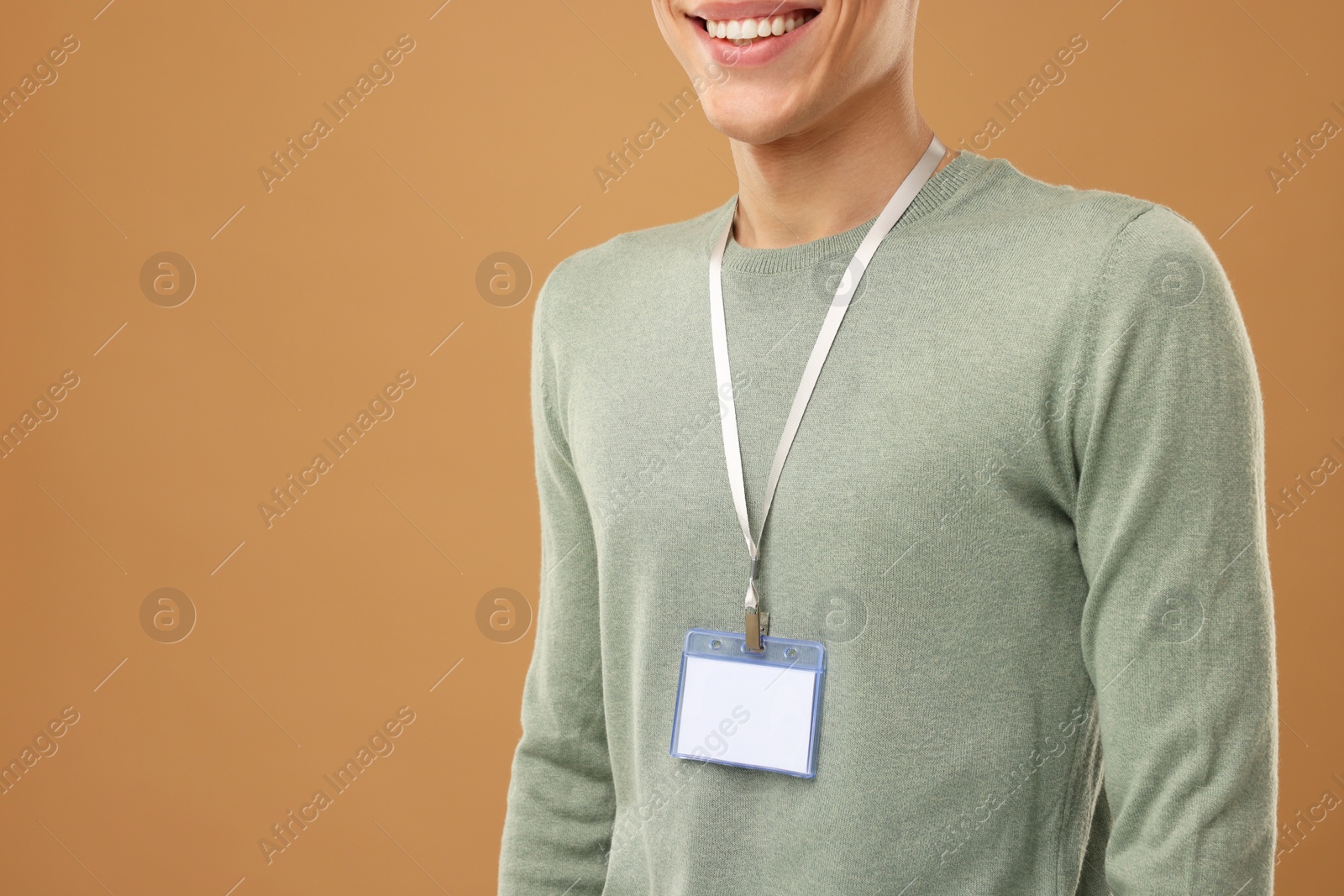 Photo of Man with blank badge on light brown background, closeup. Space for text