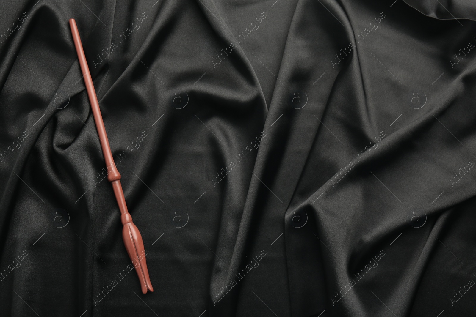 Photo of One magic wand on black fabric, top view. Space for text