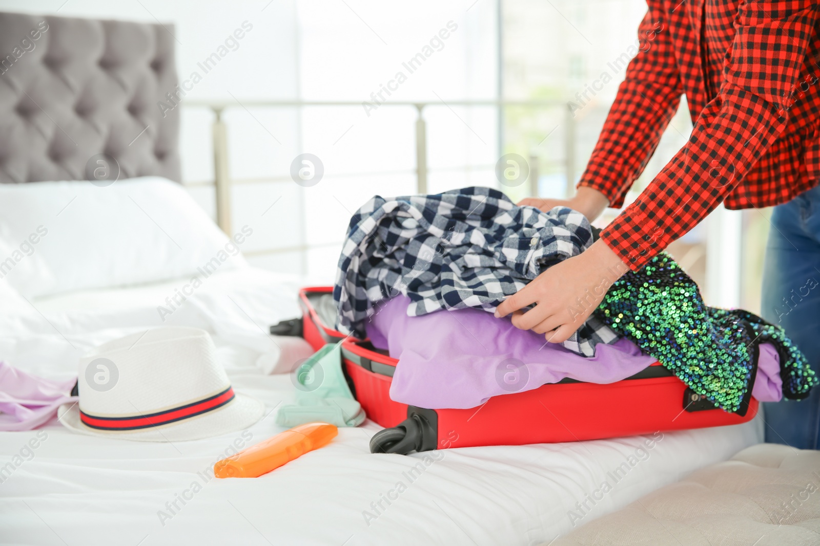 Photo of Young woman packing suitcase for summer journey at home