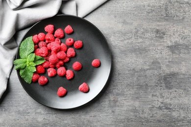 Plate with ripe aromatic raspberries on table, top view