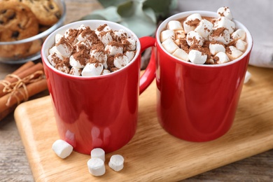 Cups of tasty cocoa with marshmallows on wooden board