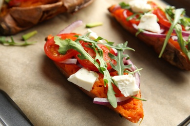 Photo of Delicious stuffed sweet potatoes on parchment, closeup