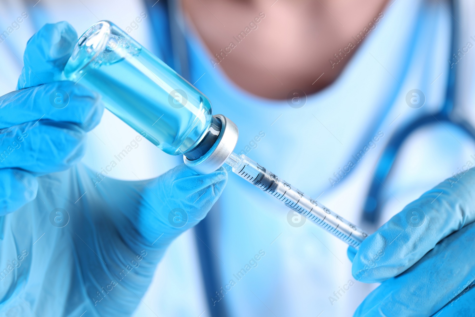 Photo of Doctor filling syringe with medication from glass vial, closeup