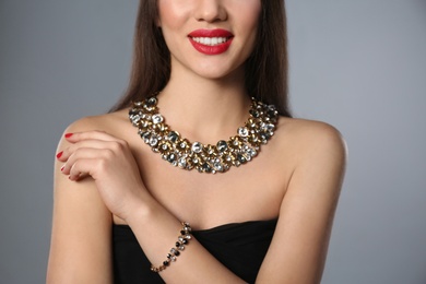Photo of Beautiful woman with stylish jewelry on grey background, closeup
