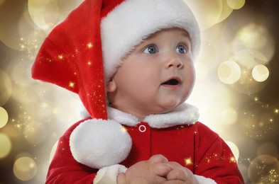 Image of Cute baby in Christmas costume against blurred festive lights, closeup