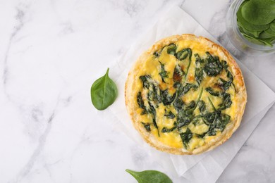 Photo of Delicious pie with spinach on white marble table, flat lay. Space for text