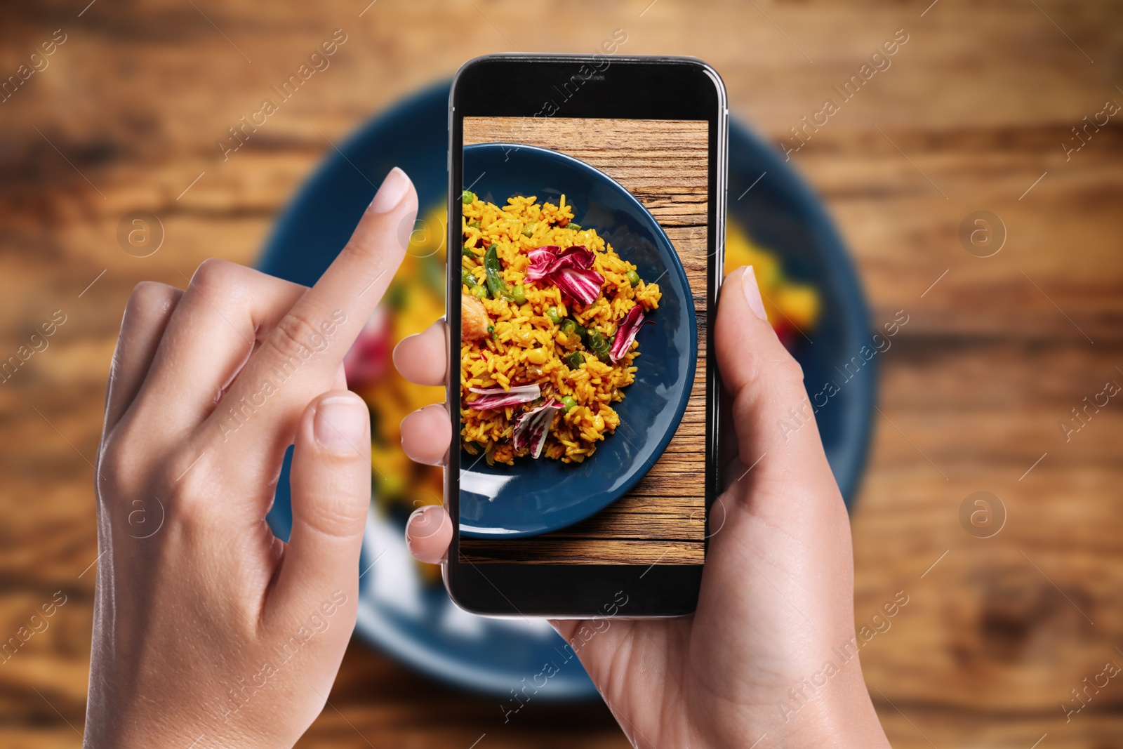 Image of Blogger taking picture of delicious pilaf with chicken and vegetables at table, closeup. Food photography