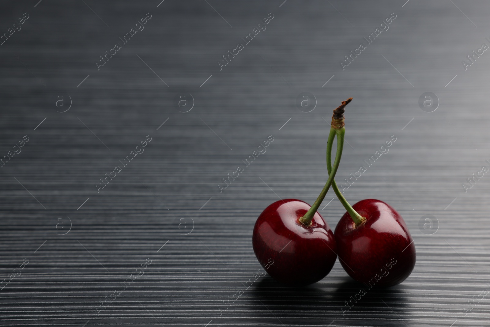 Photo of Fresh sweet cherries on dark wooden table, space for text